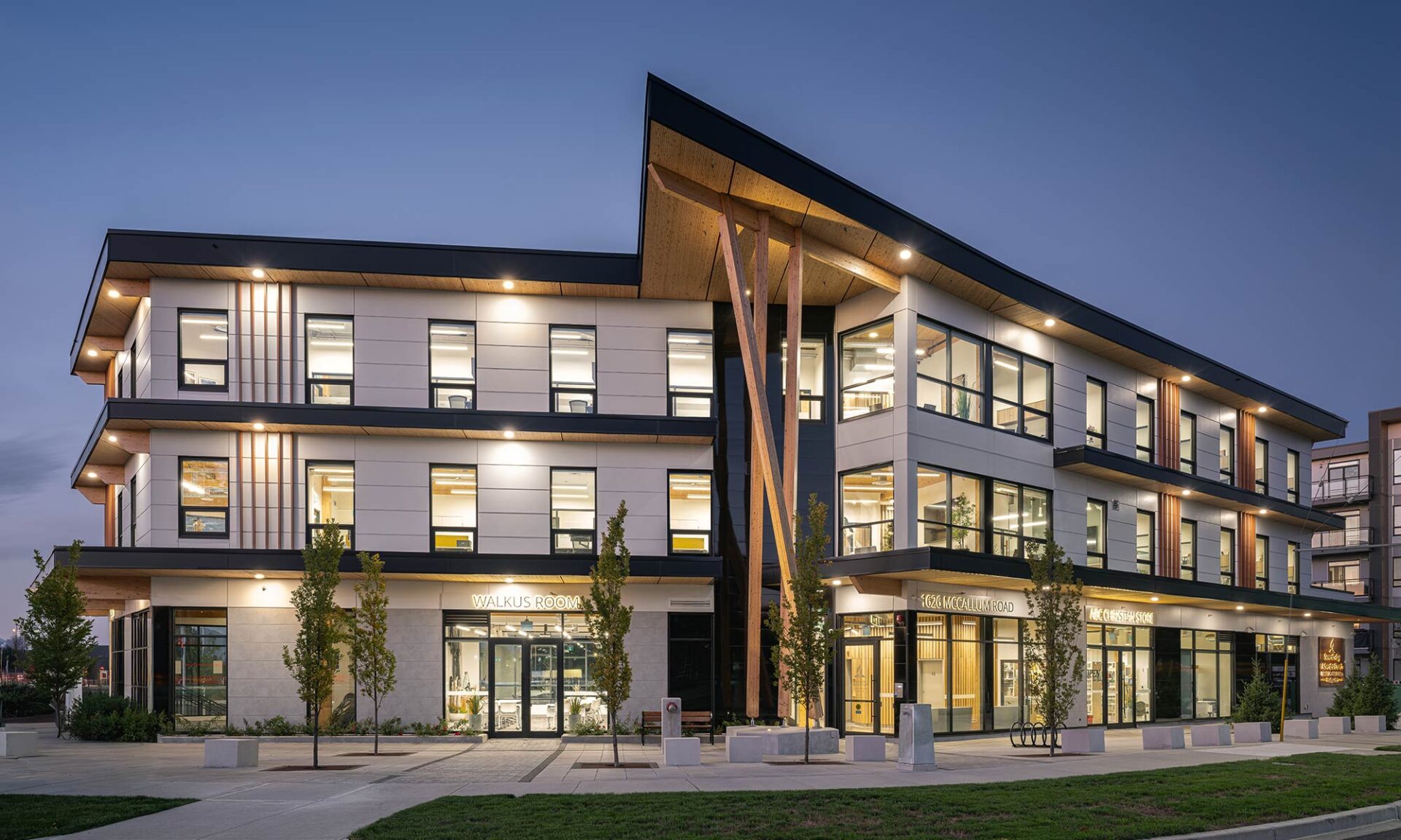 SDA office building exterior with illuminated mass timber soffit at dusk.