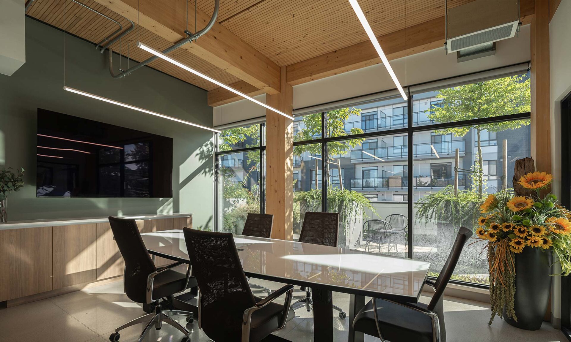 Conference room with PureEdge Pipeline suspended linear fixture above table and exposed DLT ceiling.