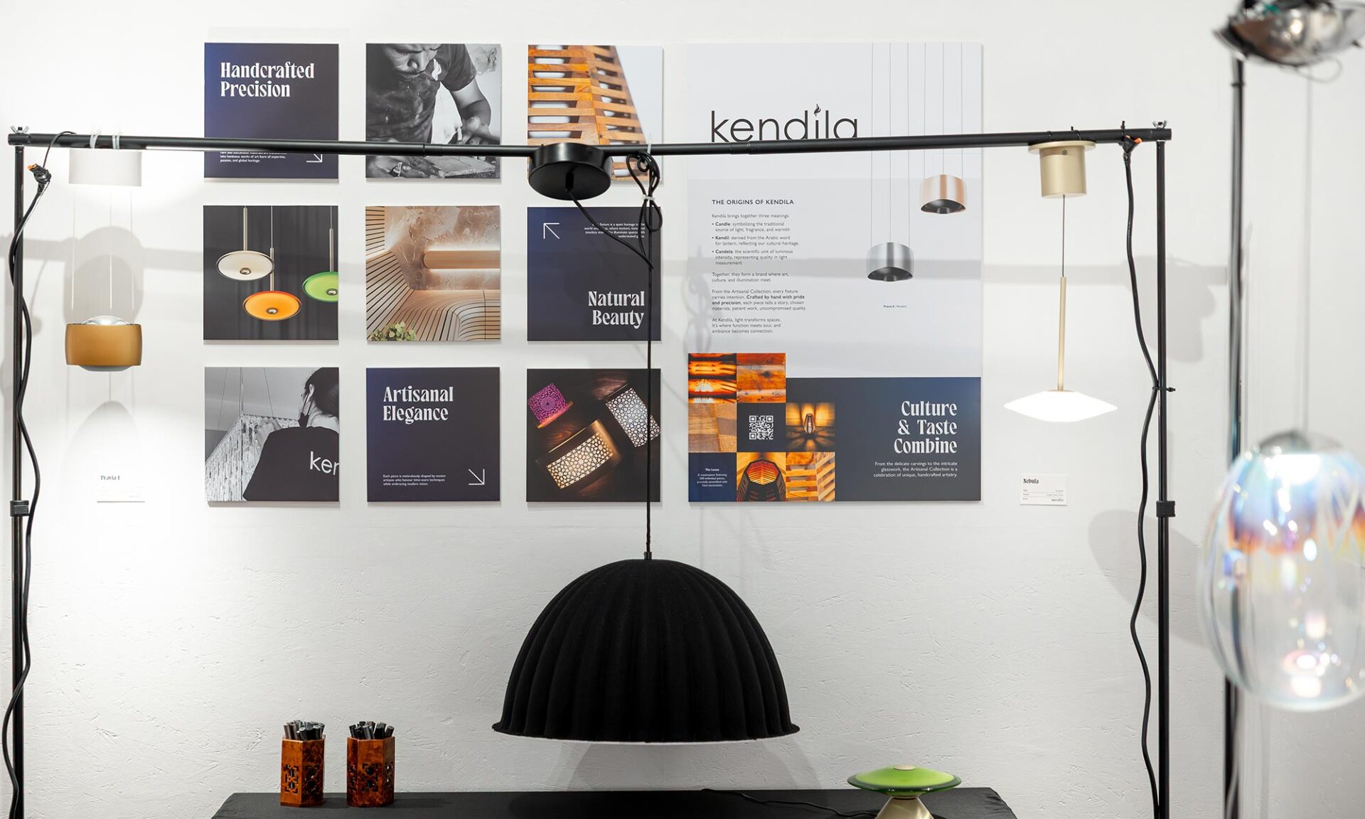 Kendila lighting display at Lumorphéa in Vancouver showing a curated selection of pendant lights hung from a black frame, including a large black dome pendant above a display table.