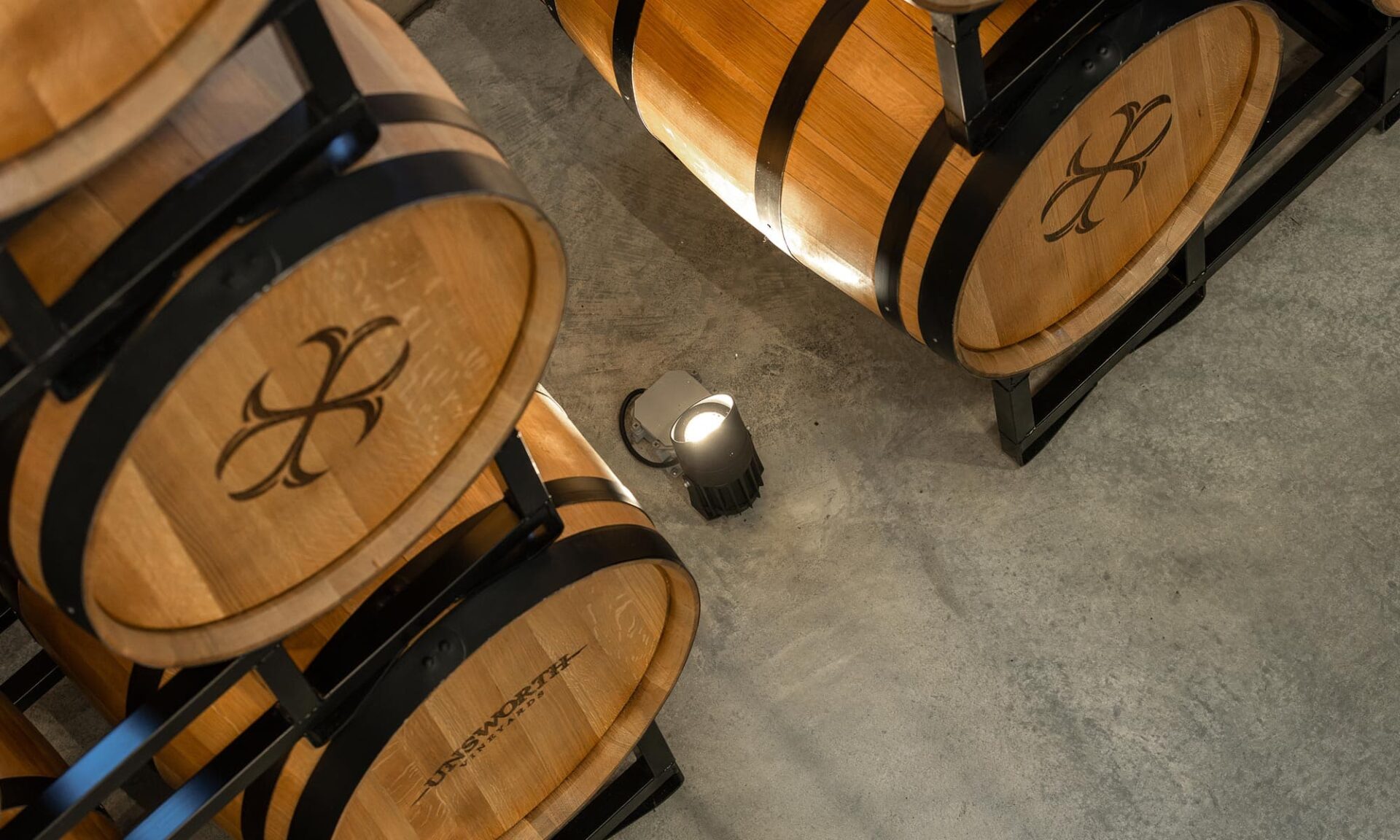 Close-up view of the Ligman Odessa small floodlight positioned at the base of Unsworth Vineyards’ barrel wall, aiming upward to illuminate the feature.