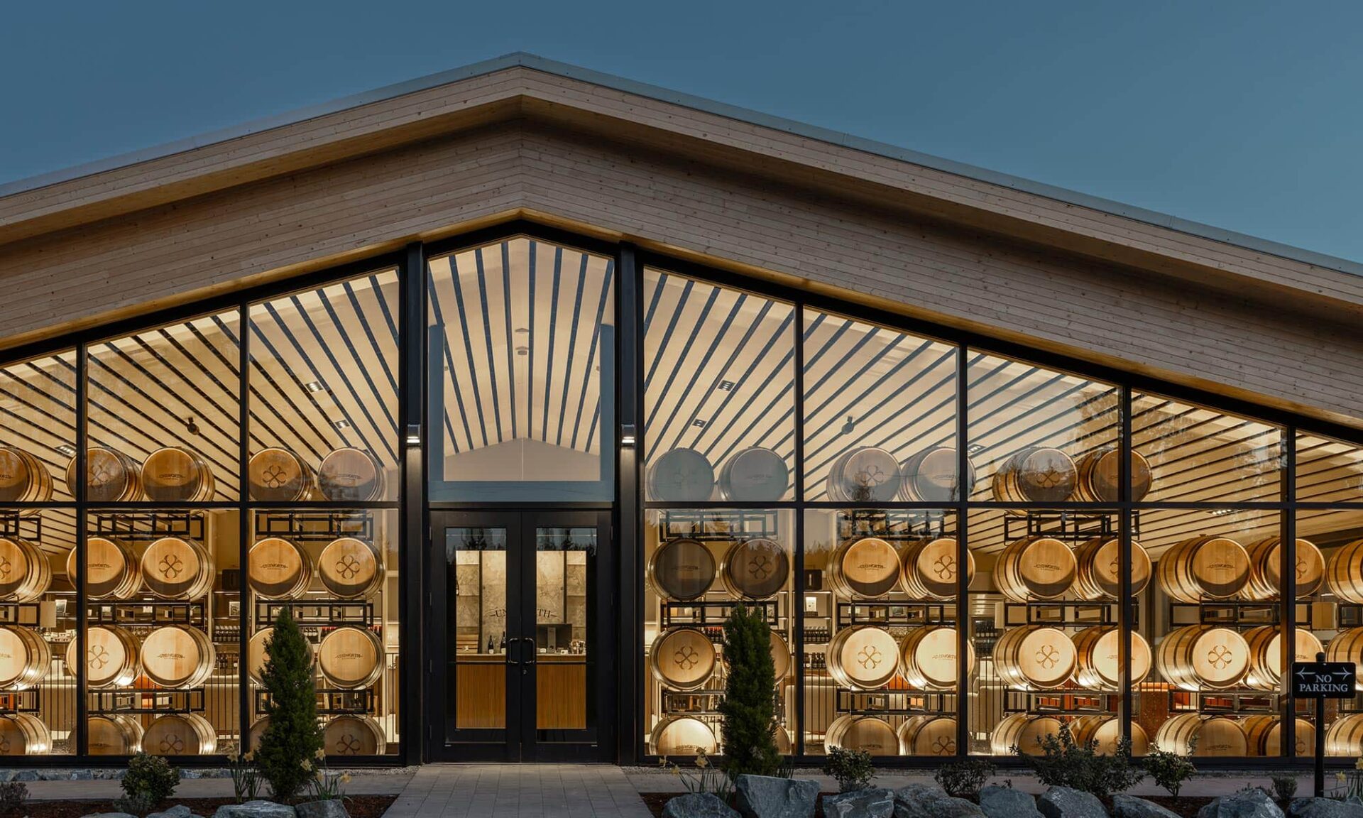 Nighttime exterior view looking into Unsworth Vineyards’ new tasting room, with warm interior lighting visible through the glazing.