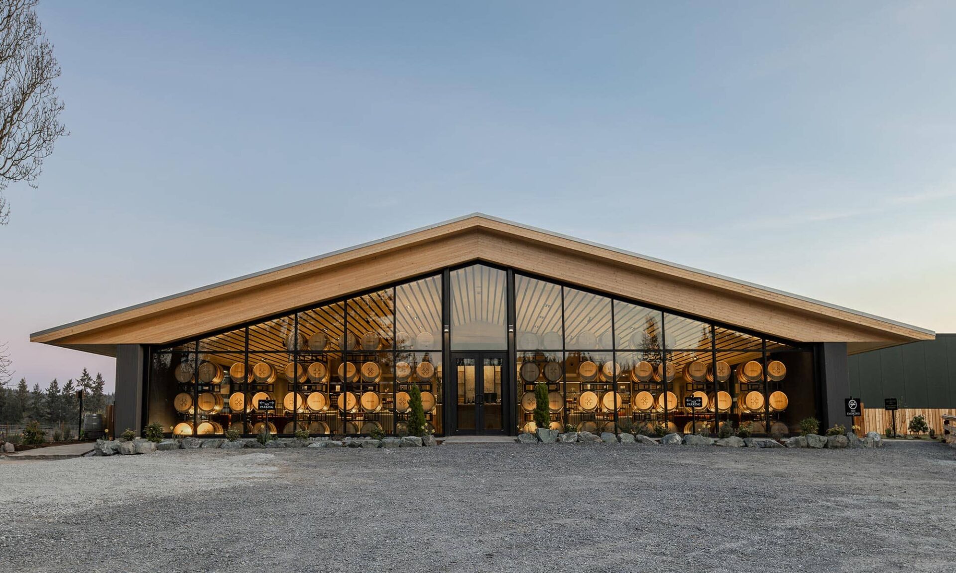 Exterior view of Unsworth Vineyards’ new tasting room at night with interior lights on, showing a warm glow through the glazing.