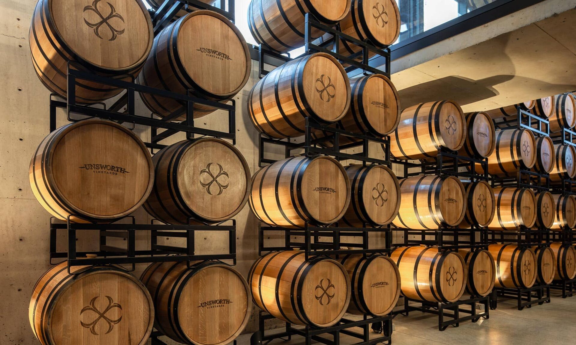 Interior view of the VIP barrel room at Unsworth Vineyards, featuring the illuminated barrel wall display and intimate, warm architectural lighting.